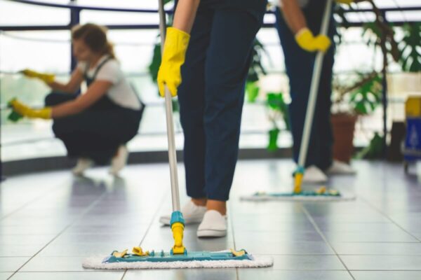 Profesjonalne sprzątanie w biurze z użyciem mopów i rękawic ochronnych.
